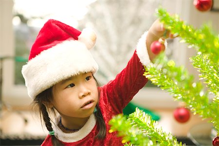 single christmas ball ornament - Girl carefully decorating Christmas tree Stock Photo - Premium Royalty-Free, Code: 673-02140590