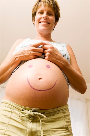 smiley - Femme enceinte avec le visage souriant sur le ventre Photographie de stock - Premium Libres de Droits, Code: 673-02140636