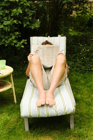 Man reading newspaper on chair in yard Stock Photo - Premium Royalty-Free, Code: 673-02140735