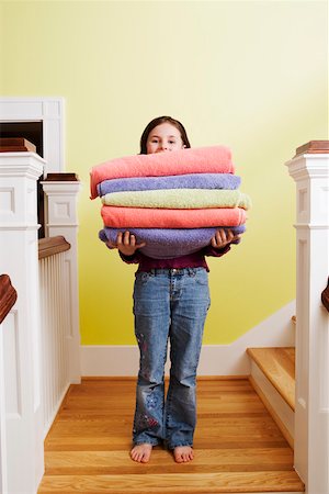 Young girl with stack of towels on stairs Stock Photo - Premium Royalty-Free, Code: 673-02140811