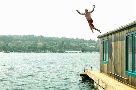 Man jumping into water from houseboat roof Foto de stock - Sin royalties Premium, Código: 673-02140884