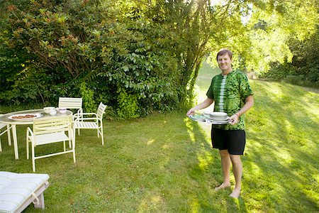 roupa tingida - Man carrying tray to table in yard Foto de stock - Royalty Free Premium, Número: 673-02140892