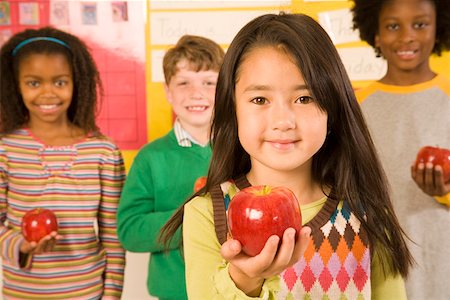 school friends standing - Portrait of girl holding apple in classroom Stock Photo - Premium Royalty-Free, Code: 673-02141895