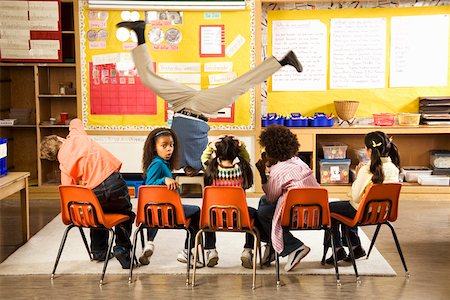 Male teacher doing handstand in classroom Foto de stock - Sin royalties Premium, Código: 673-02141905