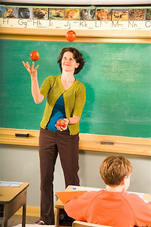 Female teacher juggling apples in classroom Foto de stock - Sin royalties Premium, Código: 673-02141900