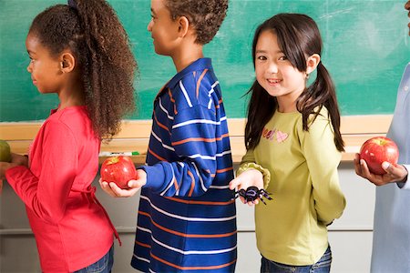 Girl holding spider in line to give apples to teacher Stock Photo - Premium Royalty-Free, Code: 673-02141920