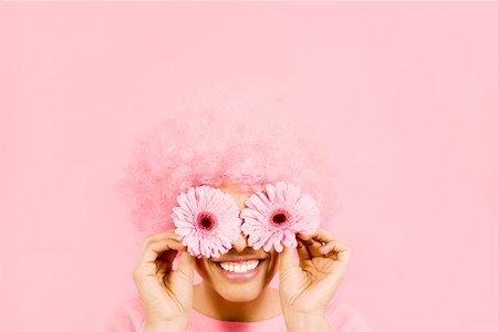 pink background designs - Woman wearing pink wig and holding flowers over eyes Stock Photo - Premium Royalty-Free, Code: 673-02142201