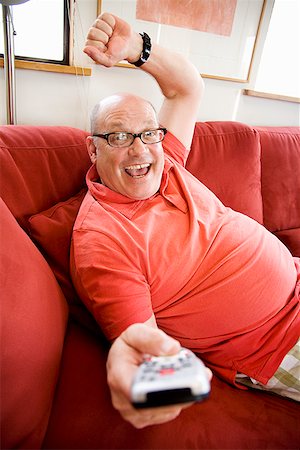 fat person arms up - Man watching television on sofa Stock Photo - Premium Royalty-Free, Code: 673-02142524