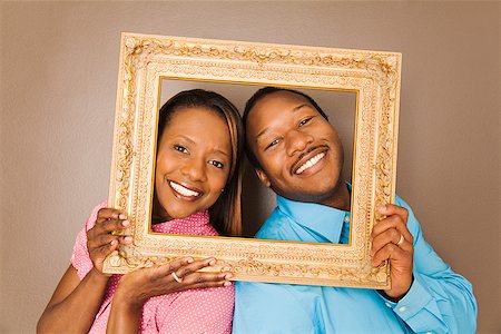 African couple looking through picture frame Foto de stock - Sin royalties Premium, Código: 673-02142834