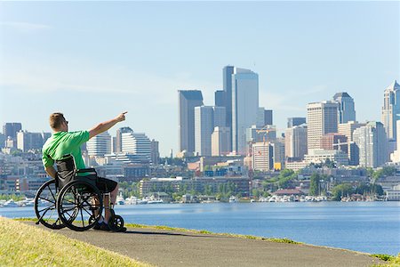 Man in wheelchair pointing at city skyline Stock Photo - Premium Royalty-Free, Code: 673-02142866