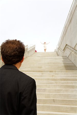 stair climbing - Businessman looking at businesswoman at top of steps Stock Photo - Premium Royalty-Free, Code: 673-02142986