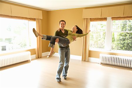 Hispanic man carrying wife in new house Stock Photo - Premium Royalty-Free, Code: 673-02143044