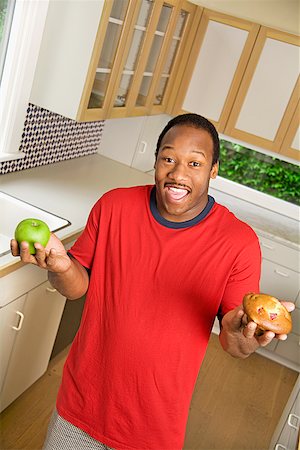 simsearch:673-02143792,k - African man holding apple and muffin Foto de stock - Sin royalties Premium, Código: 673-02143114