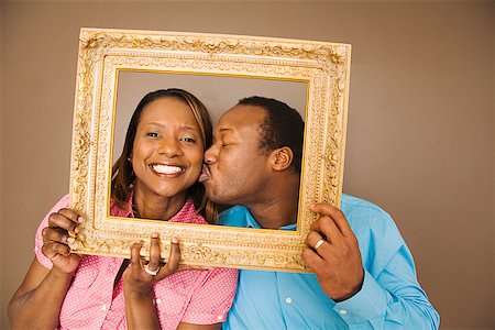 simsearch:673-02143137,k - African man kissing wife in picture frame Fotografie stock - Premium Royalty-Free, Codice: 673-02143134