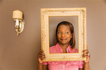 simsearch:673-02143137,k - African woman looking through picture frame Fotografie stock - Premium Royalty-Free, Codice: 673-02143140