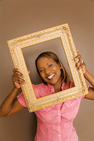 simsearch:673-02143137,k - African woman looking through picture frame Fotografie stock - Premium Royalty-Free, Codice: 673-02143141