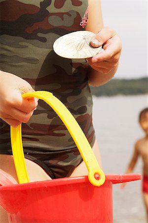 Girl holding sand dollar and pail Stock Photo - Premium Royalty-Free, Code: 673-02143321