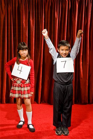 school boy hand up raised - Asian boy wearing number and cheering on stage Stock Photo - Premium Royalty-Free, Code: 673-02143369