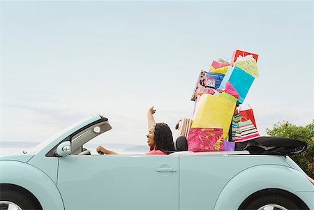 excited african american in a car - African woman in convertible with shopping bags Stock Photo - Premium Royalty-Free, Code: 673-02143386