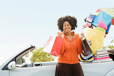 African woman next to car filled with shopping bags Stock Photo - Premium Royalty-Free, Code: 673-02143383