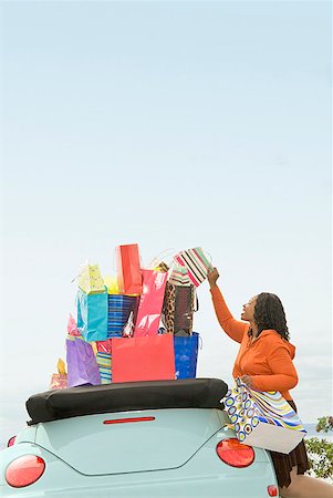excess - African woman next to convertible with shopping bags Stock Photo - Premium Royalty-Free, Code: 673-02143403