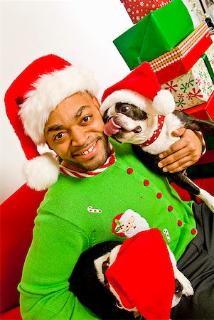 simsearch:673-02143801,k - African man and dogs wearing Santa Claus hats Fotografie stock - Premium Royalty-Free, Codice: 673-02143811