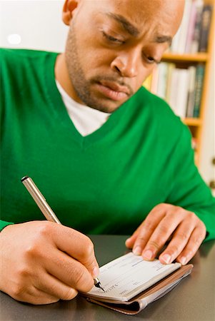 person writing in check book - African man writing check Stock Photo - Premium Royalty-Free, Code: 673-02143894