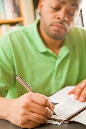 person writing in check book - African man writing check Stock Photo - Premium Royalty-Free, Code: 673-02143891