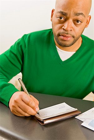 African man writing check Stock Photo - Premium Royalty-Free, Code: 673-02143902