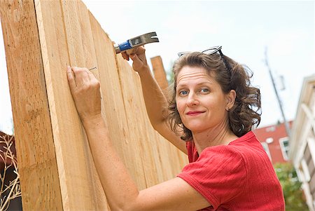 Woman hammering nail into fence Foto de stock - Sin royalties Premium, Código: 673-02143915