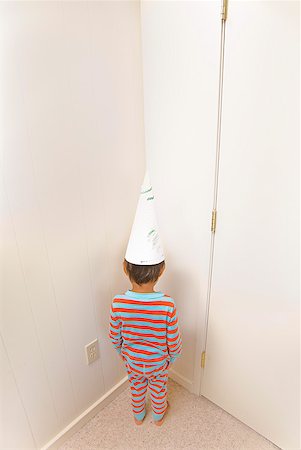 funny depressed - Boy wearing dunce cap in corner Stock Photo - Premium Royalty-Free, Code: 673-02143925