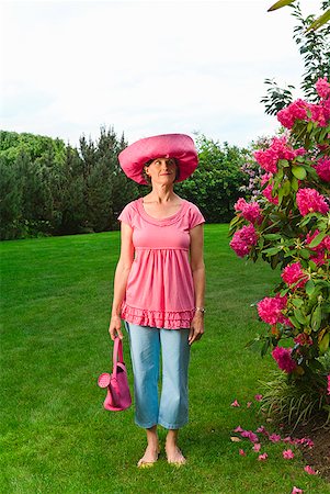 Woman in festive pink hat standing in garden Stock Photo - Premium Royalty-Free, Code: 673-02216246