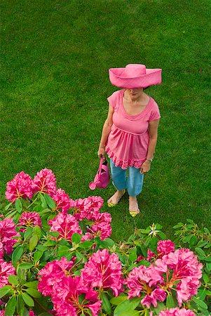 Woman in festive pink hat standing in garden Stock Photo - Premium Royalty-Free, Code: 673-02216253