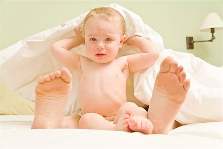 simsearch:673-02143588,k - Sad baby and mother’s feet under blanket in bed Foto de stock - Royalty Free Premium, Número: 673-02216293