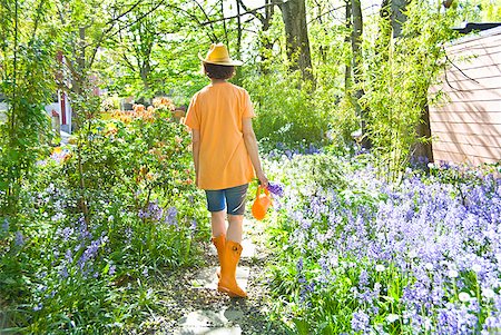 Woman walking through flowered path in garden Stock Photo - Premium Royalty-Free, Code: 673-02216320