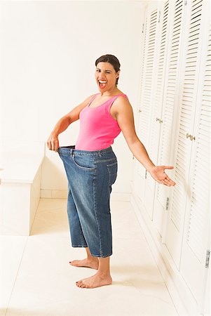 Excited woman in big pants showing off weight loss Stock Photo - Premium Royalty-Free, Code: 673-02216365