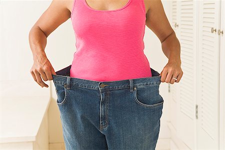 Woman in big pants showing off weight loss Stock Photo - Premium Royalty-Free, Code: 673-02216369