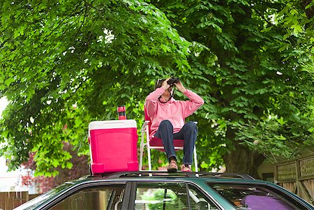 Woman with binoculars picnicking on top of car Stock Photo - Premium Royalty-Free, Code: 673-02216556