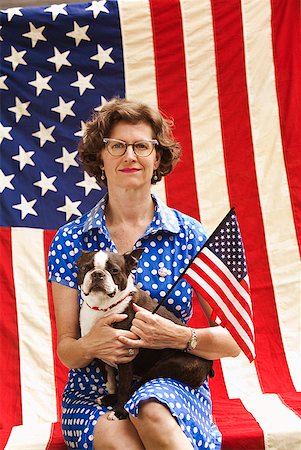 Patriotic woman and Boston Terrier dog posing with American flag Stock Photo - Premium Royalty-Free, Code: 673-02216553