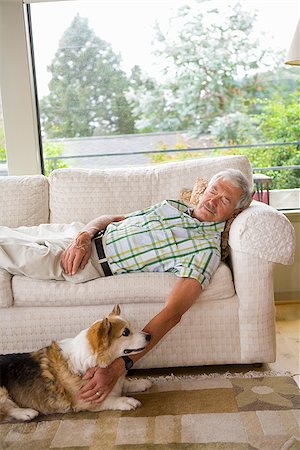 simsearch:673-02386328,k - Man napping on a couch with his dog sitting beside him Foto de stock - Sin royalties Premium, Código: 673-02386334