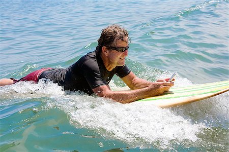 surfboard mobile - Man floating on water and text messaging Stock Photo - Premium Royalty-Free, Code: 673-02386415