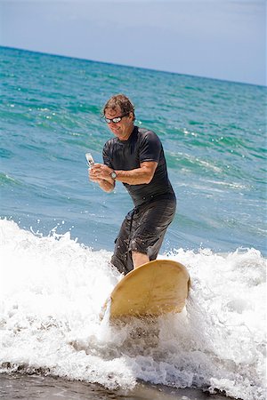 surfboard mobile - Man surfing in the sea and using a mobile phone Stock Photo - Premium Royalty-Free, Code: 673-02386515