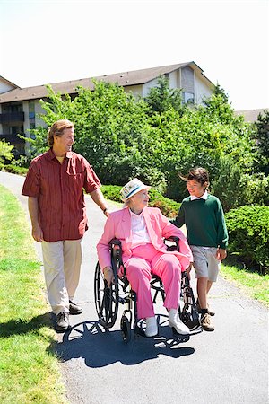 Man with a girl assisting a woman in a wheelchair Stock Photo - Premium Royalty-Free, Code: 673-02386540