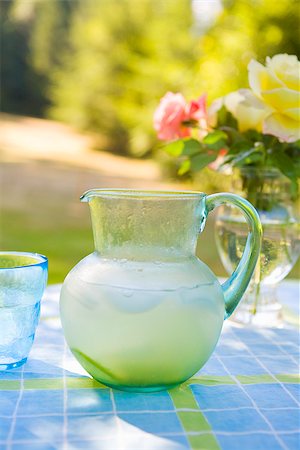 Jug of lemonade with a glass and a flower vase on a table Fotografie stock - Premium Royalty-Free, Codice: 673-02386552