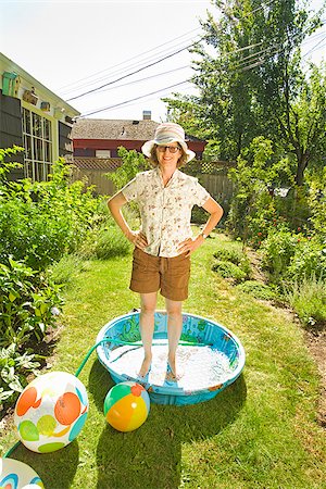 Woman standing in a wading pool with arms akimbo Stock Photo - Premium Royalty-Free, Code: 673-02386573