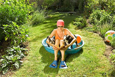 dog in heat - Woman reading a book in a wading pool between two Boston Terriers Foto de stock - Sin royalties Premium, Código: 673-02386607