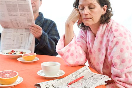 simsearch:673-02801248,k - Tired woman with her husband at breakfast looking at classifieds Stock Photo - Premium Royalty-Free, Code: 673-02801282