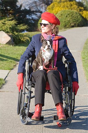 Woman in wheelchair with dog on her lap Stock Photo - Premium Royalty-Free, Code: 673-02801299