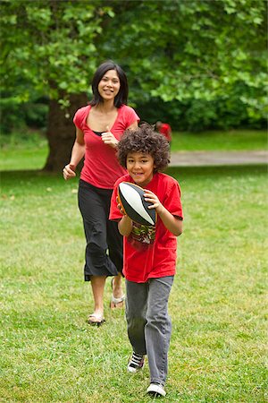 Boy with football running from mother Stock Photo - Premium Royalty-Free, Code: 673-03005599