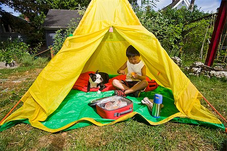 Boy with dogs in backyard tent Stock Photo - Premium Royalty-Free, Code: 673-03005649